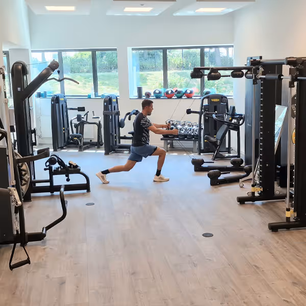 Großer Trainingsbereich der Rheinblick Physio. Ole Nauert, Therapeut und Inhaber der Rheinblick Physio, zeigt eine Übung an der Kinesis. 