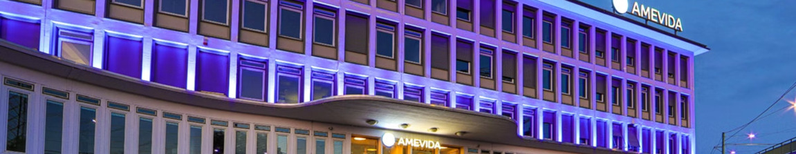 Beleuchtetes Gebäude der AMEVIDA SE bei Nacht.