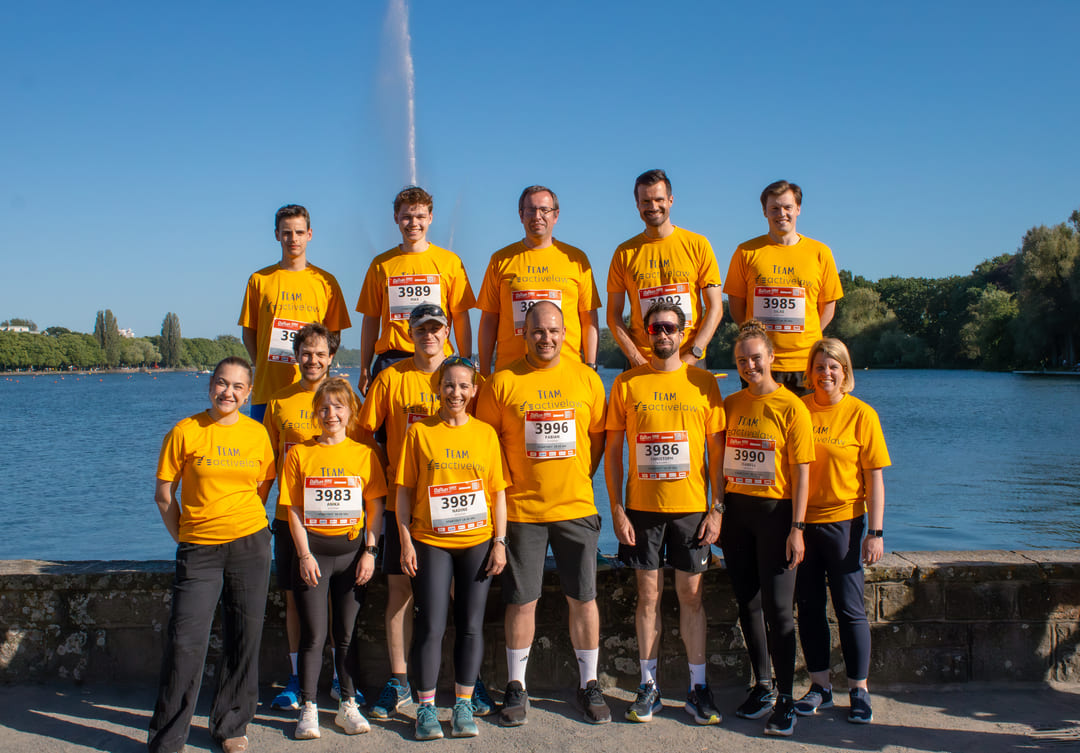 Das Team activelaw in gelben Laufshirts mit Startnummern steht vor dem Maschsee.