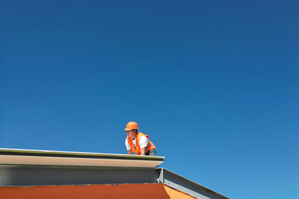 Ein Bauarbeiter arbeitet auf dem Dach eines Gebäudes.