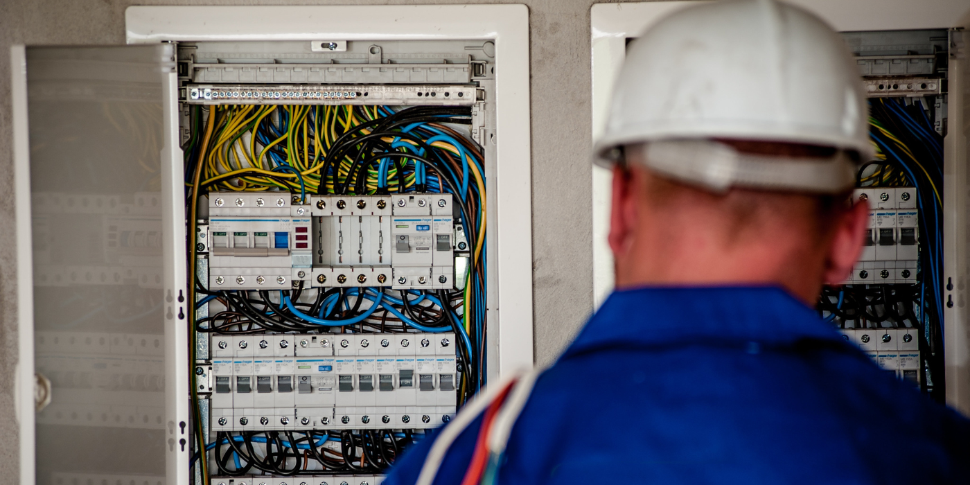 Bati-Mat - Technicien inspectant un tableau électrique complexe rempli de câbles colorés