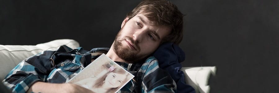 Man holding photo, looking pensive.