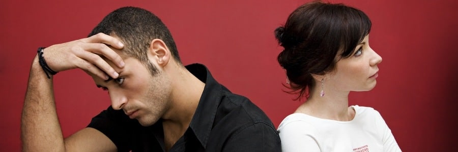 Couple sitting back-to-back, man looking down, woman looking away.