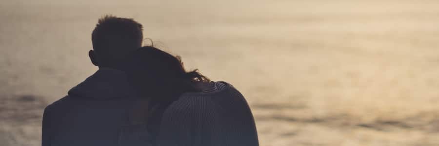 Couple sitting by sunset sea.