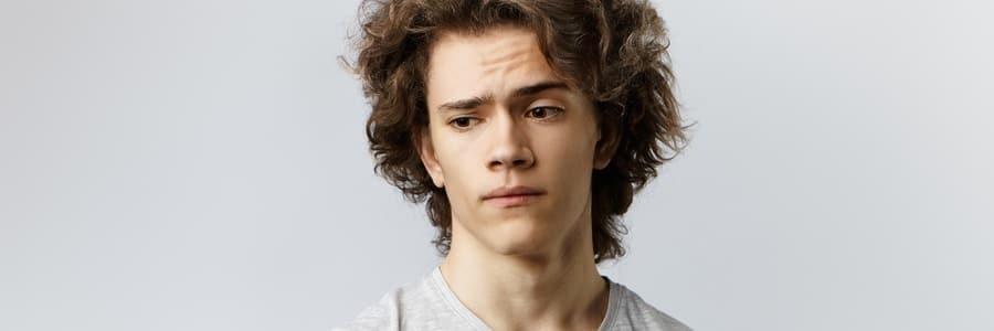 Young man with curly hair looking pensive.