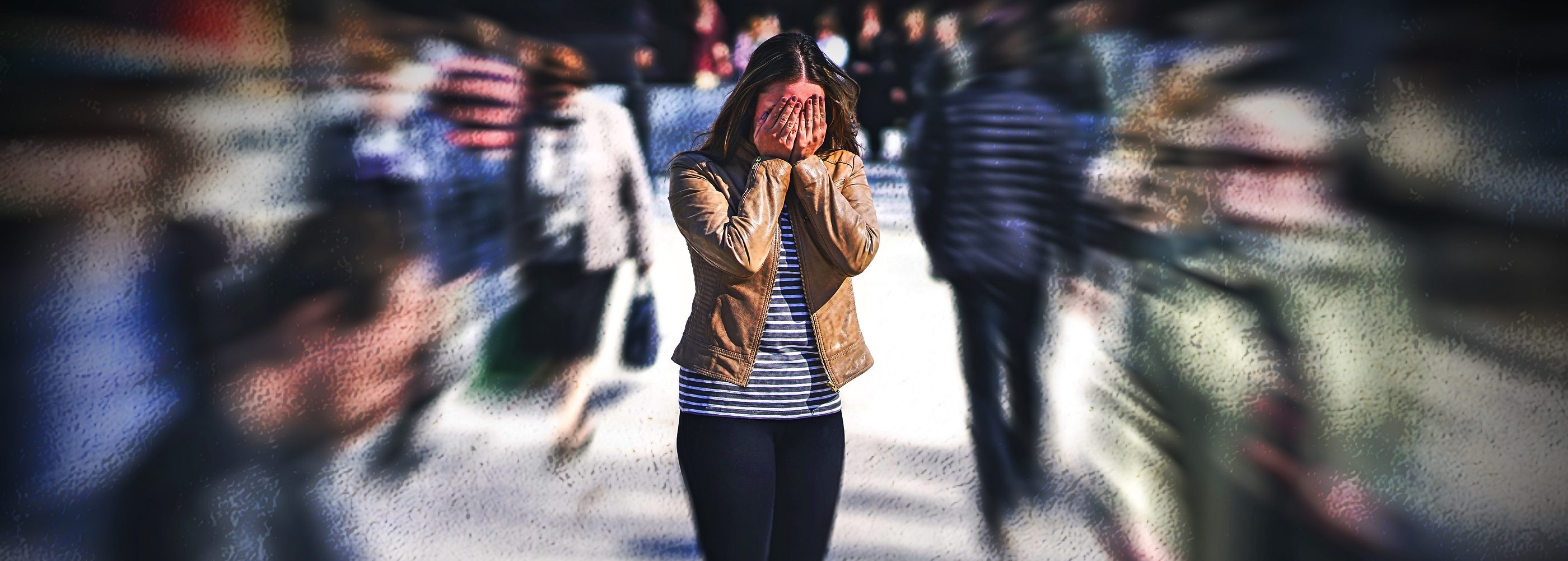 Woman covering face in busy street.