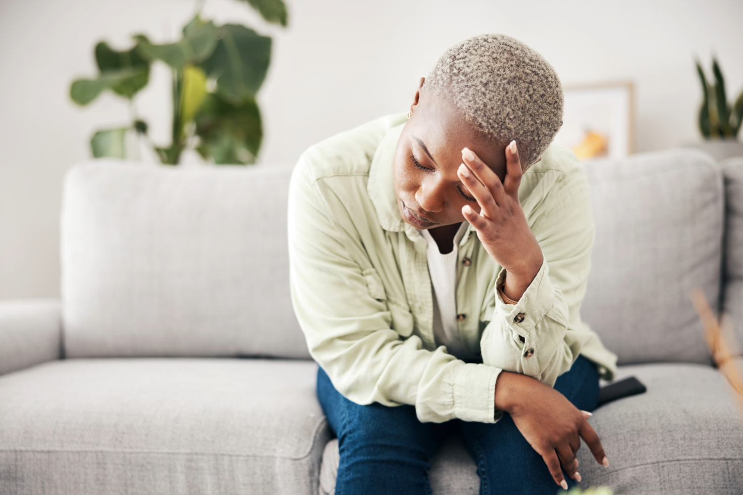 Woman sitting pensively on a couch.