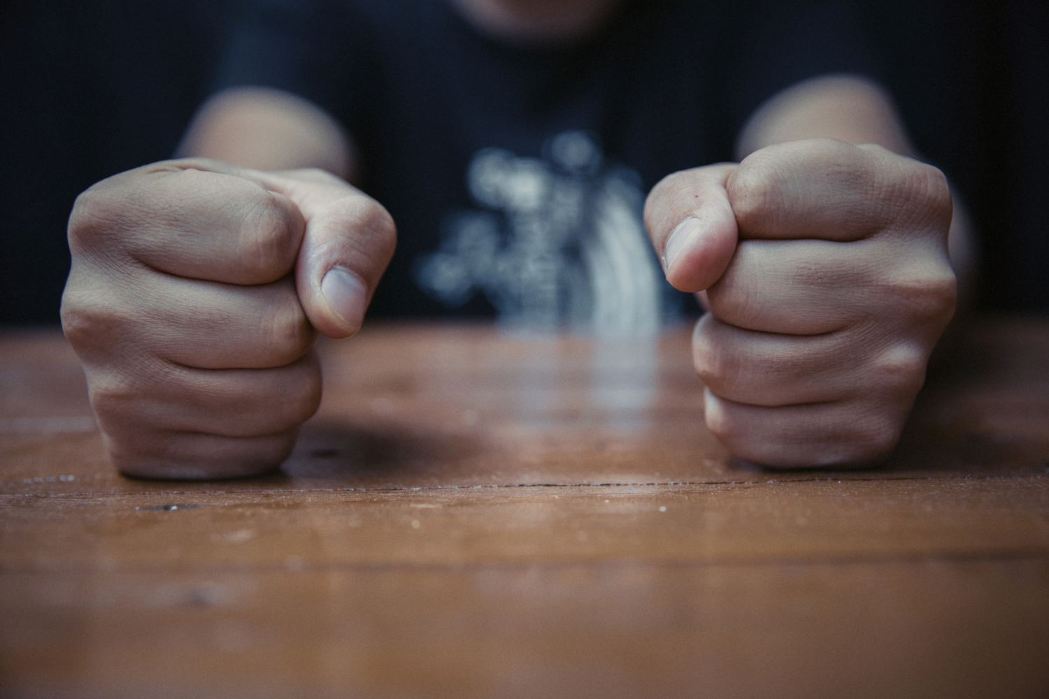 Clenched fists on wooden table.