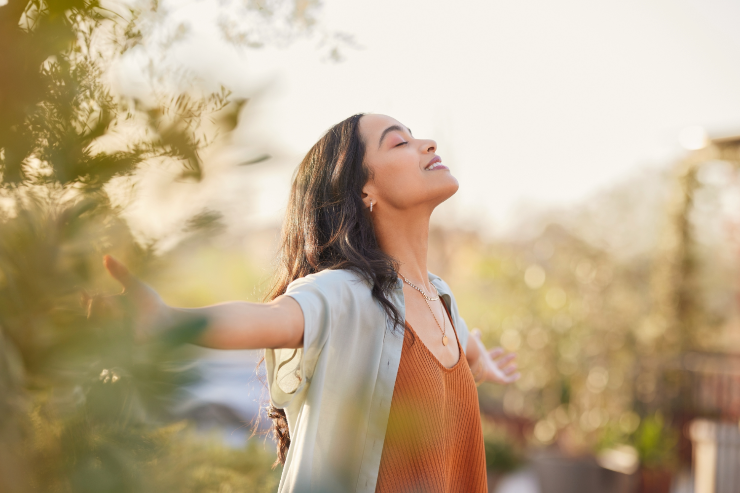 Woman joyfully embracing sunlight outdoors.