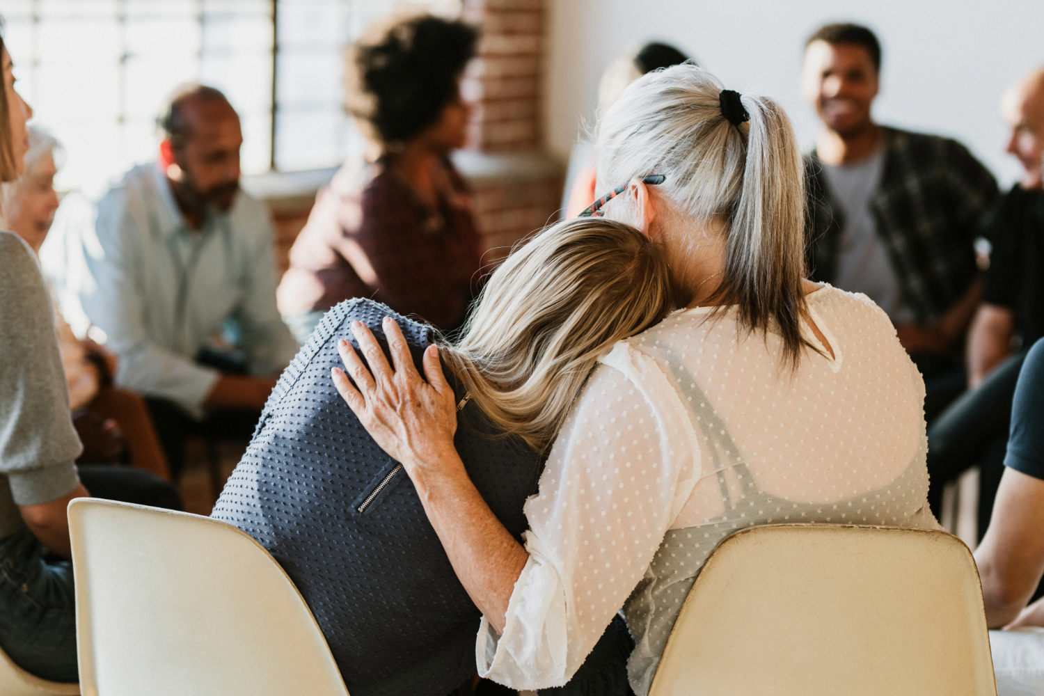 Group therapy session, woman comforting another.