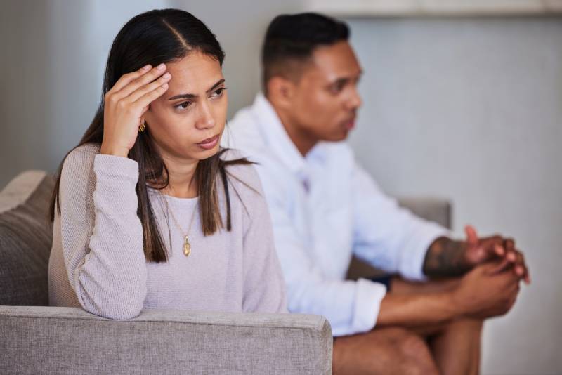 A couple looking distressed on a sofa.