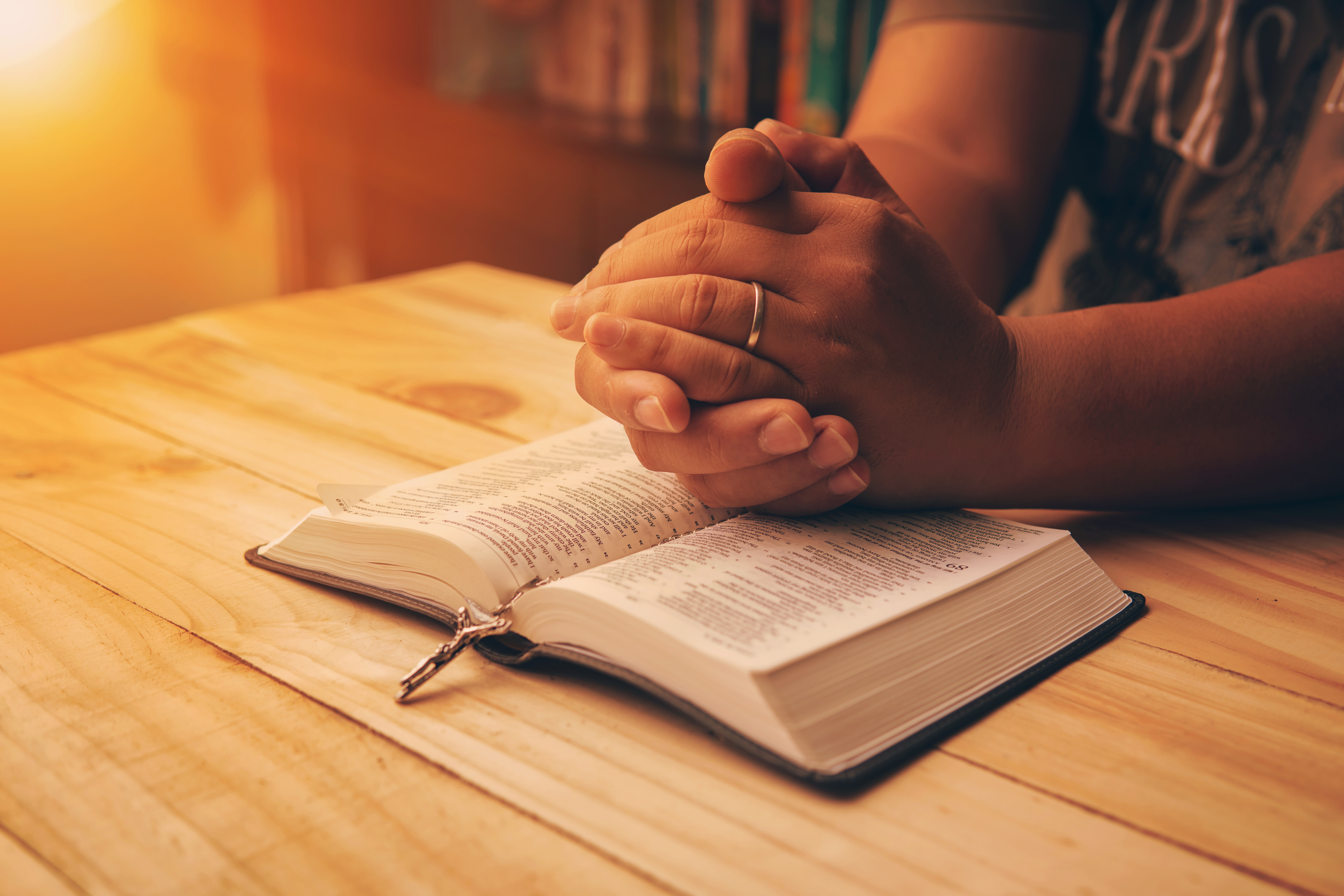 Hands praying over an open Bible.
