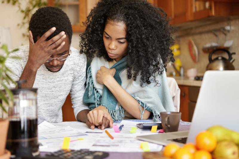 Couple stressed over bills at kitchen table.