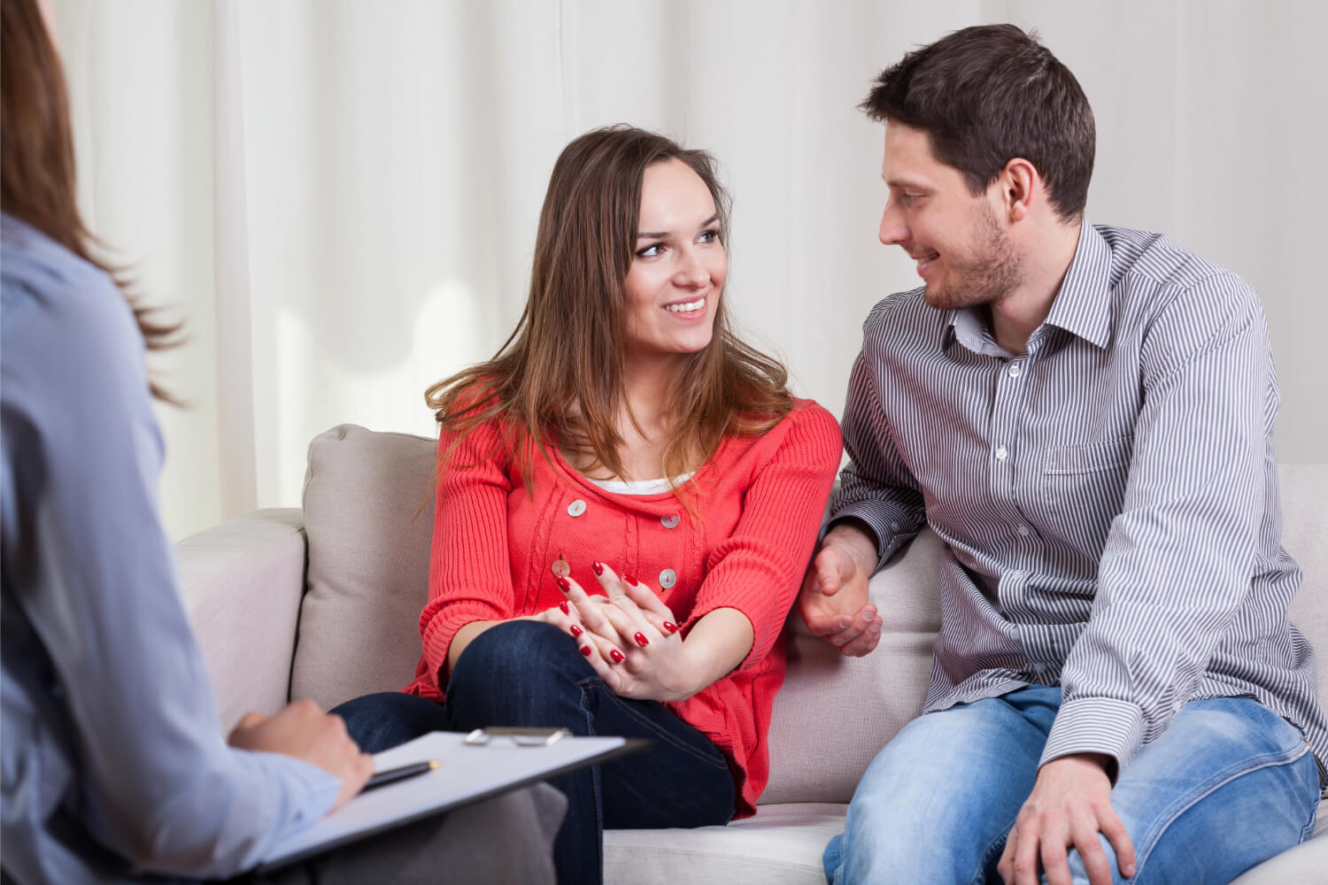 Couple smiles during therapy session with counselor.