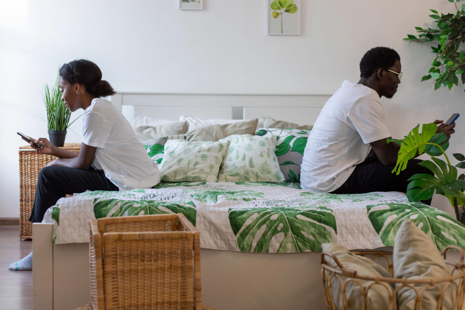 Couple back-to-back on bed, using phones.