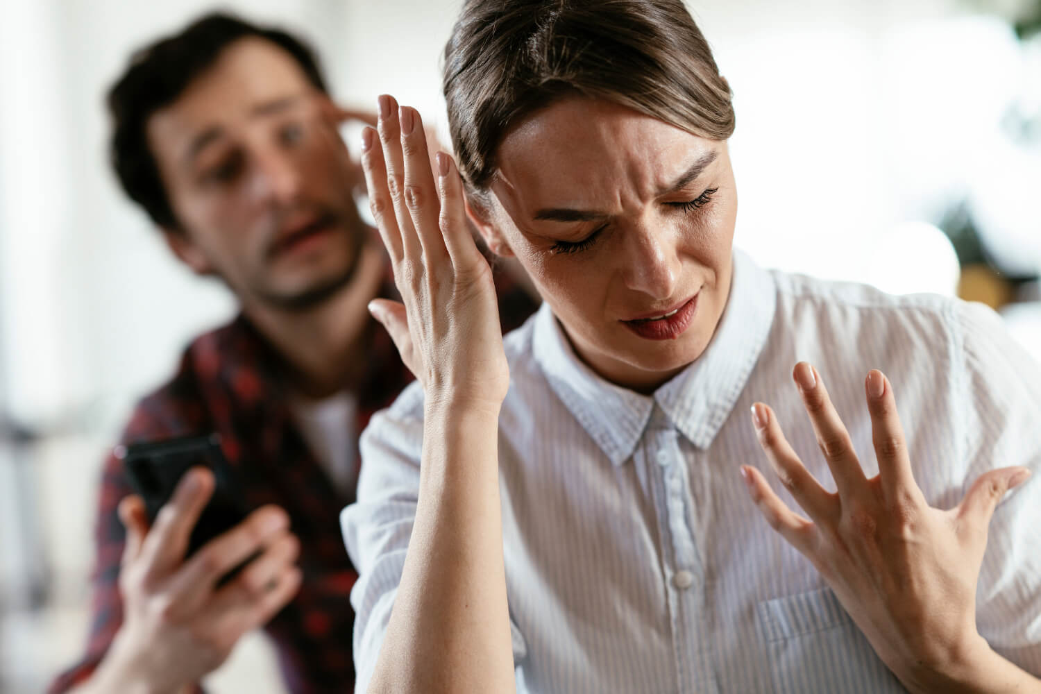 Woman appearing upset, man in background talking.