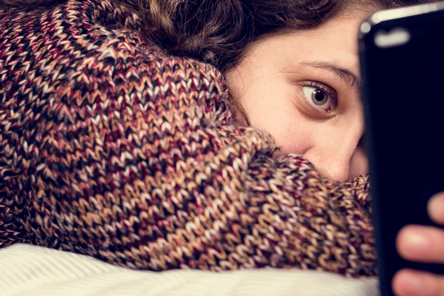 Person in sweater looking at phone.