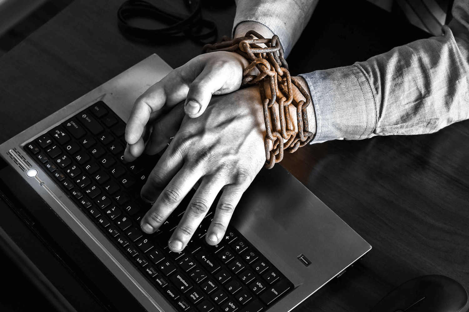 Hands chained over laptop keyboard.