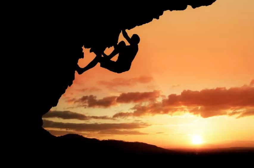 Silhouette of a climber on a rock face at sunset.