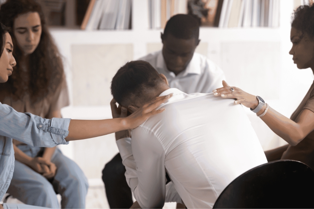 Support group comforting grieving man.