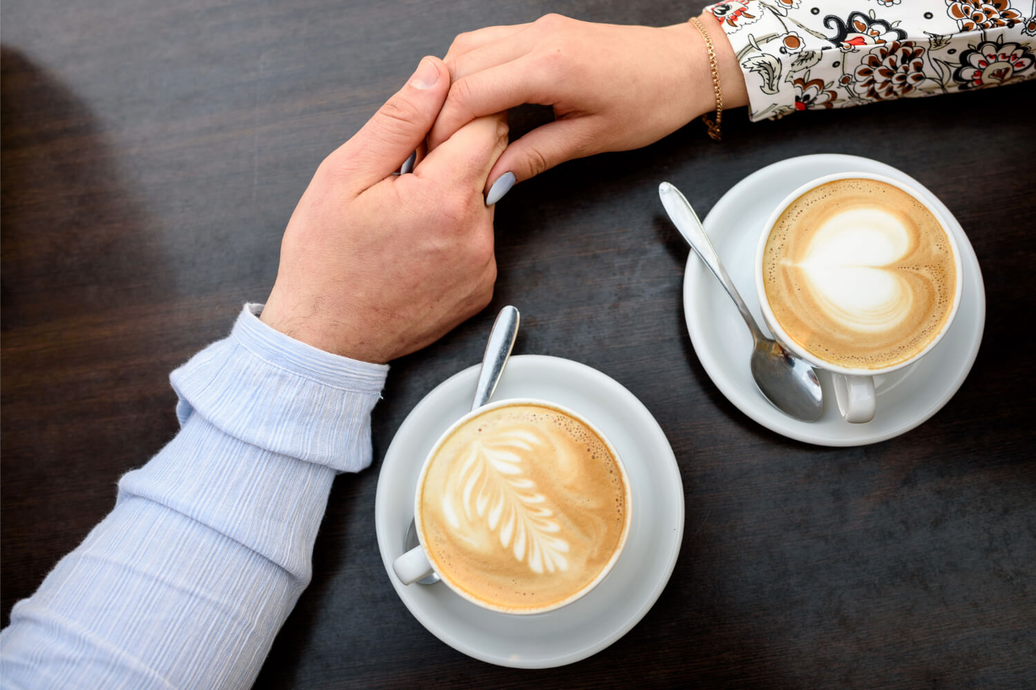 Two lattes, couple holding hands