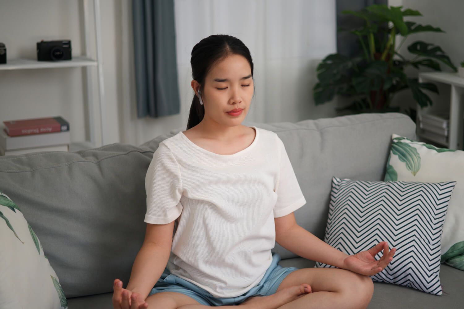 Woman meditating on couch with headphones.
