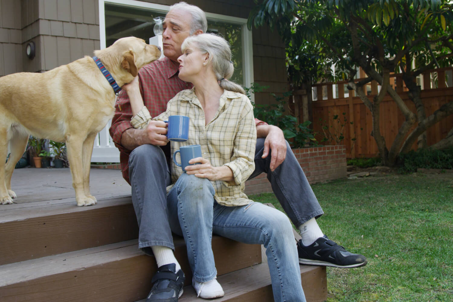 Elderly couple with dog on porch.