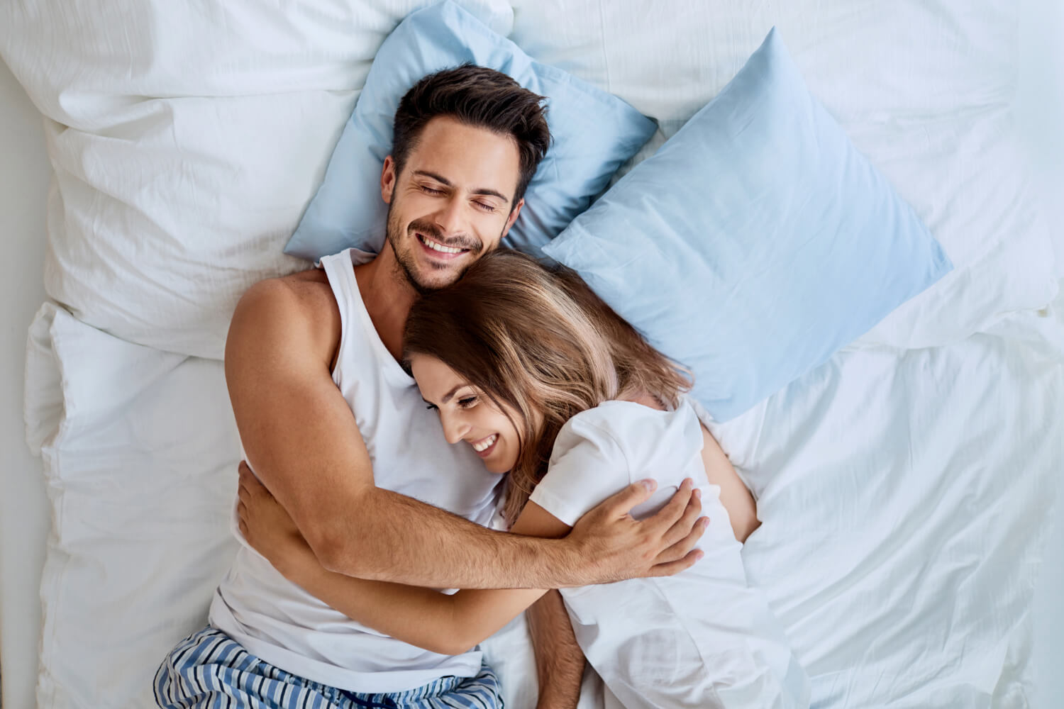 Happy couple hugging in bed.