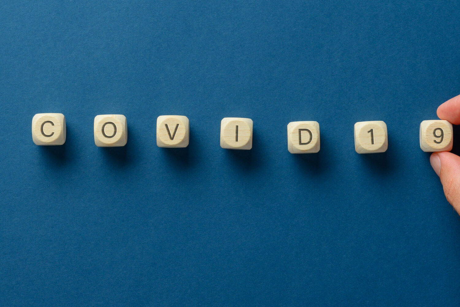 Wooden blocks spell "COVID19" on blue background.