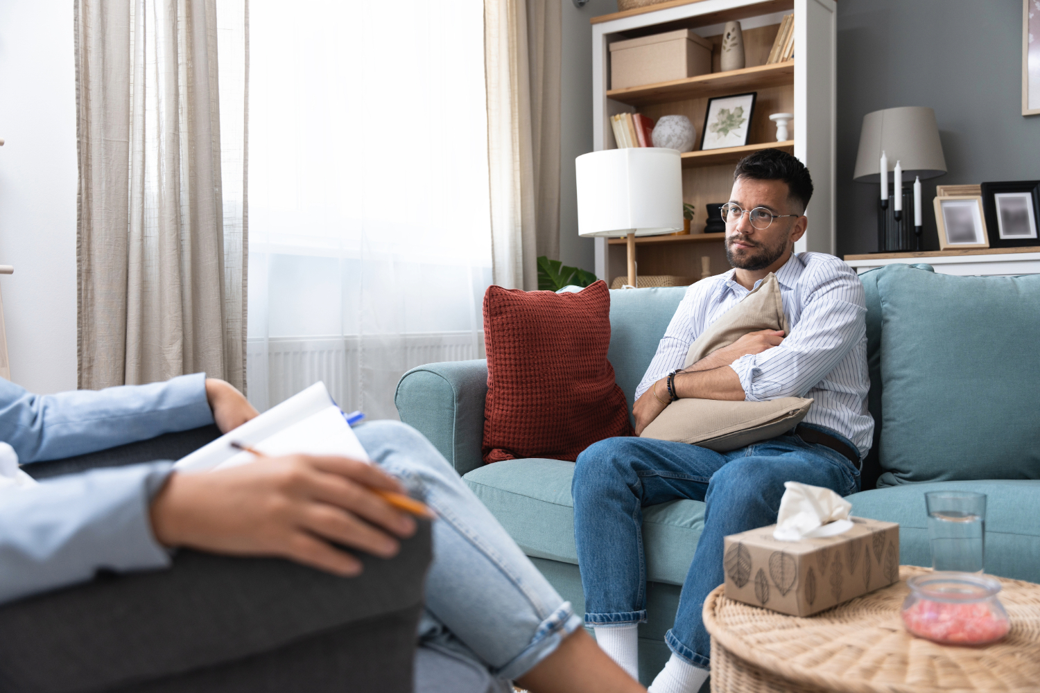 Man holding pillow on couch in therapy session.