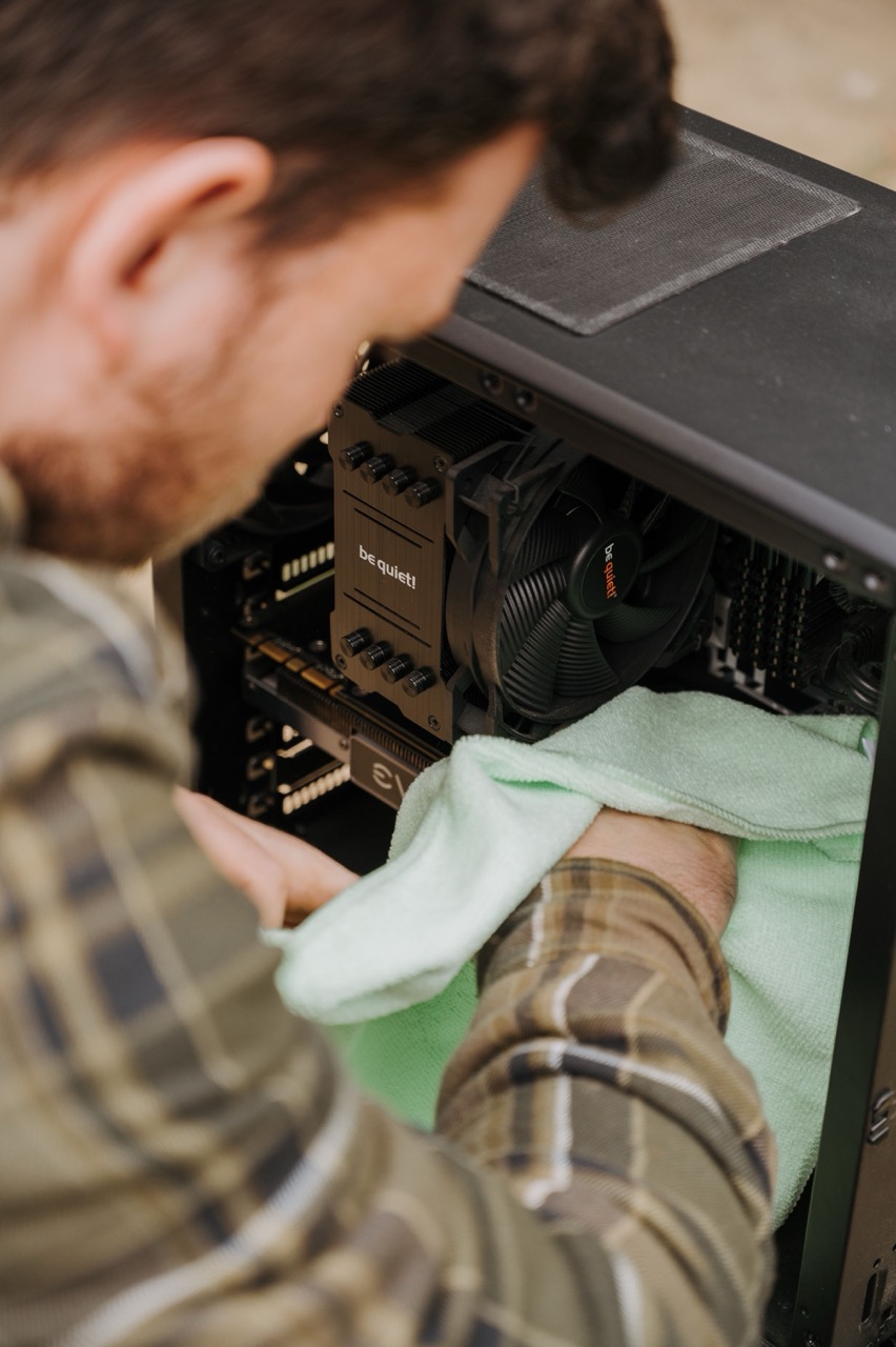A professional cleaning the inside of a computer