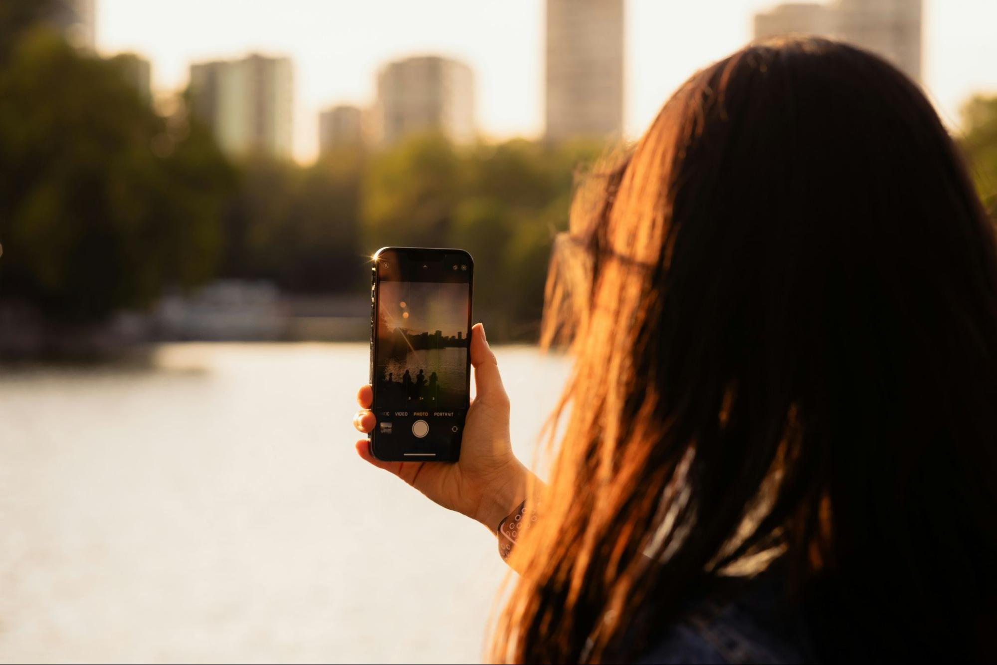 Woman taking a photo of a city skyline with her smartphone