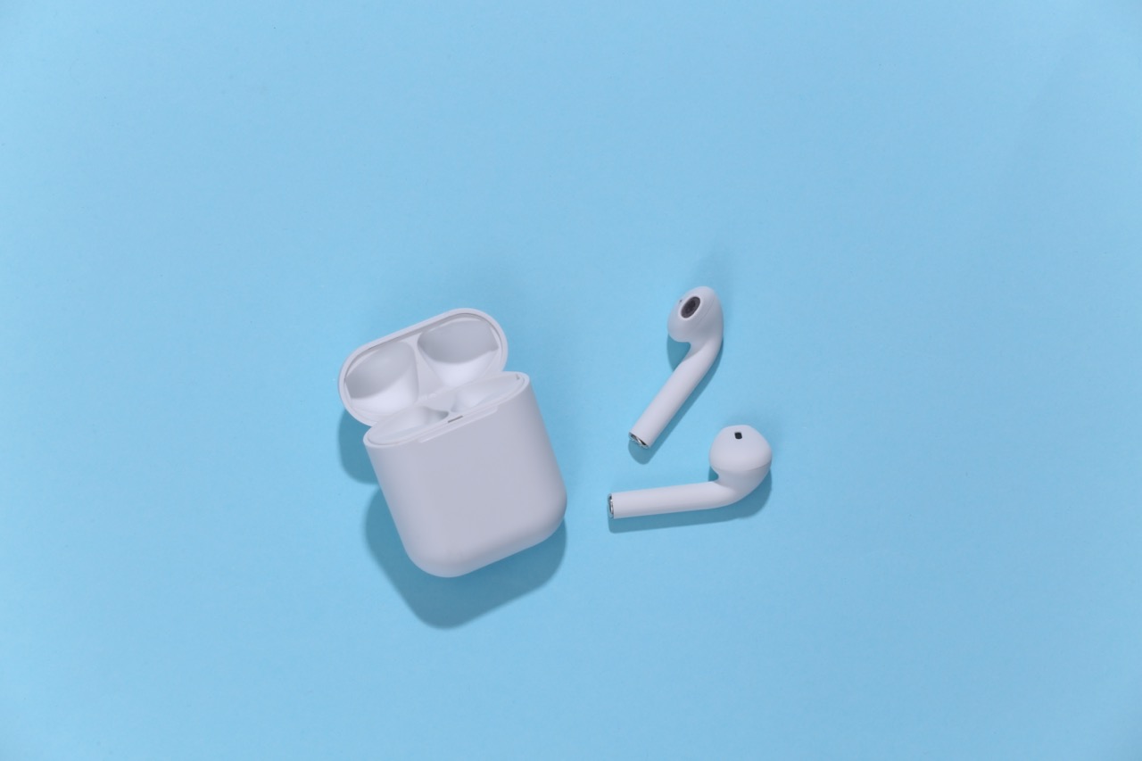White wireless earbuds and charging case on a blue background