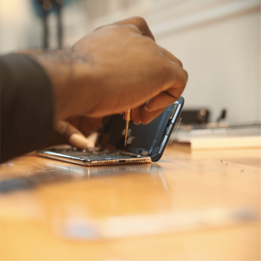 Technician's hands repairing an opened smartphone at a workbench