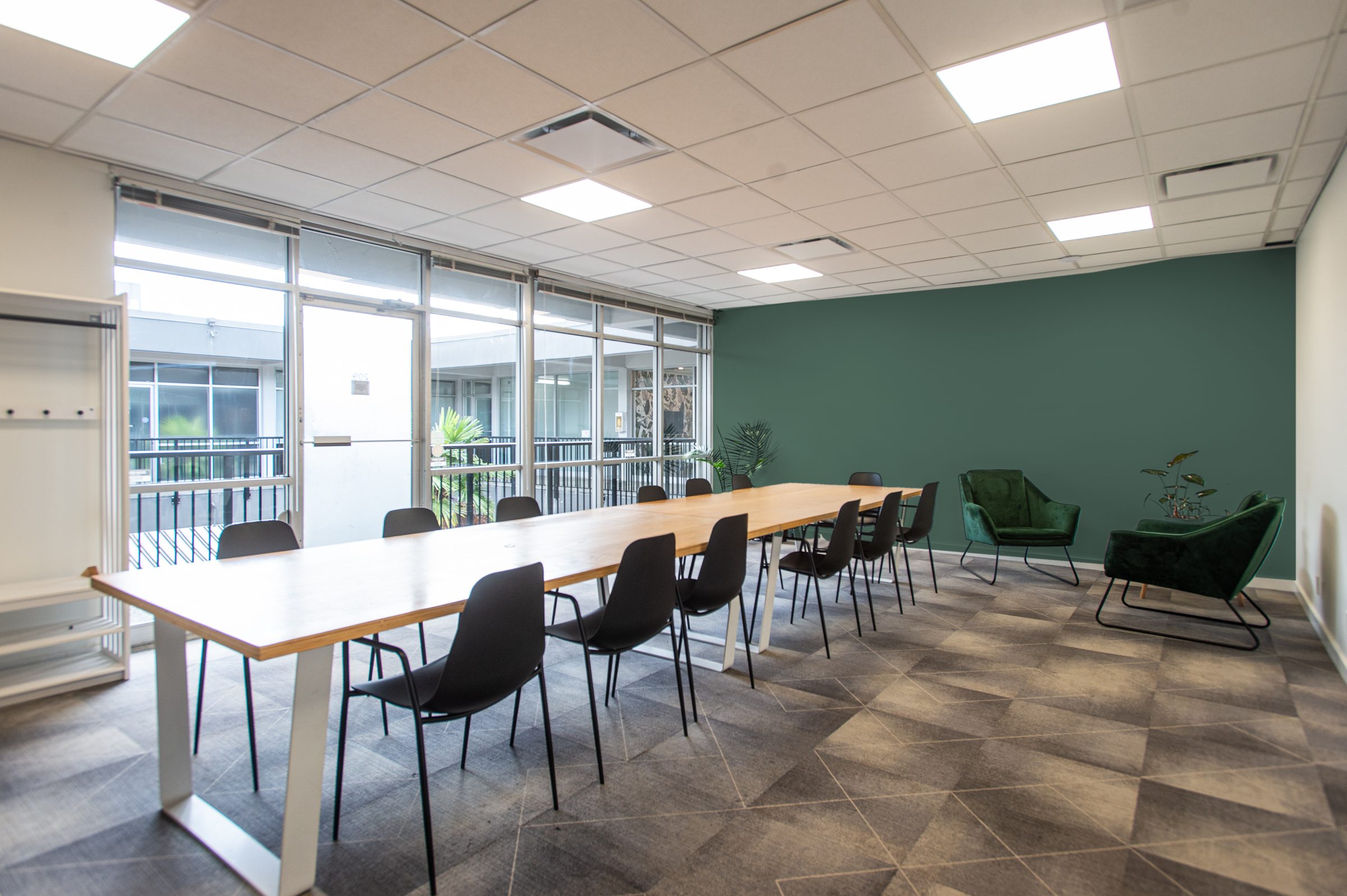 The Kitsilano Meeting Space with a long table for 15, a green feature wall and lounge chairs
