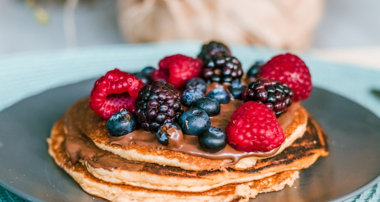 A plate of pancakes with fresh fruit on top.