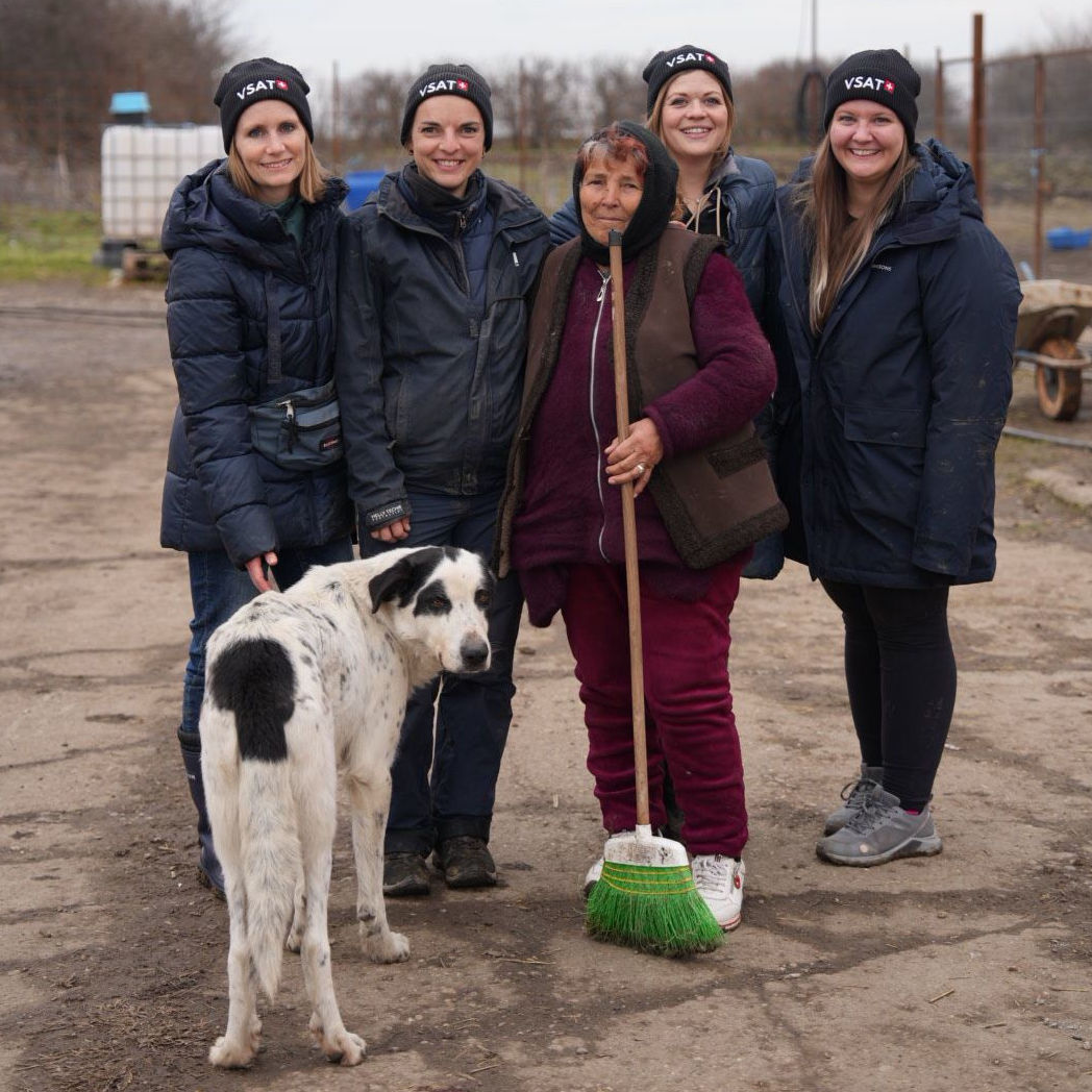 Eine Gruppe von sieben Personen sitzt gemeinsam an einem gedeckten Tisch in einem Restaurant, lächelt in die Kamera.