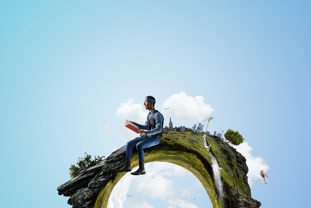 a man reading a book sitting on planet earth