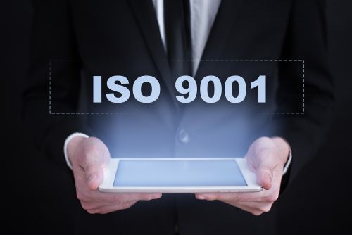 a man holds a screen with ISO 9001 projecting