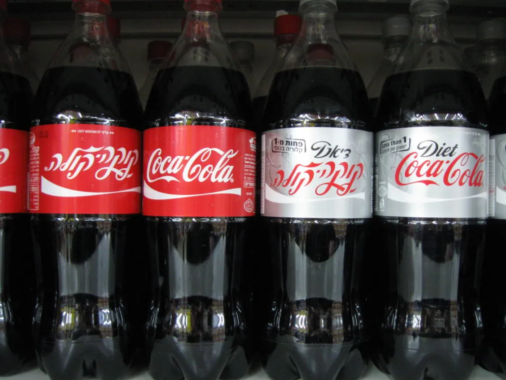 diet coca cola and regular coca cola 2 litre bottles kept side by side on a shelf