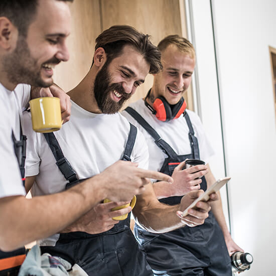 Handwerker schauen ins Telefon und lachen