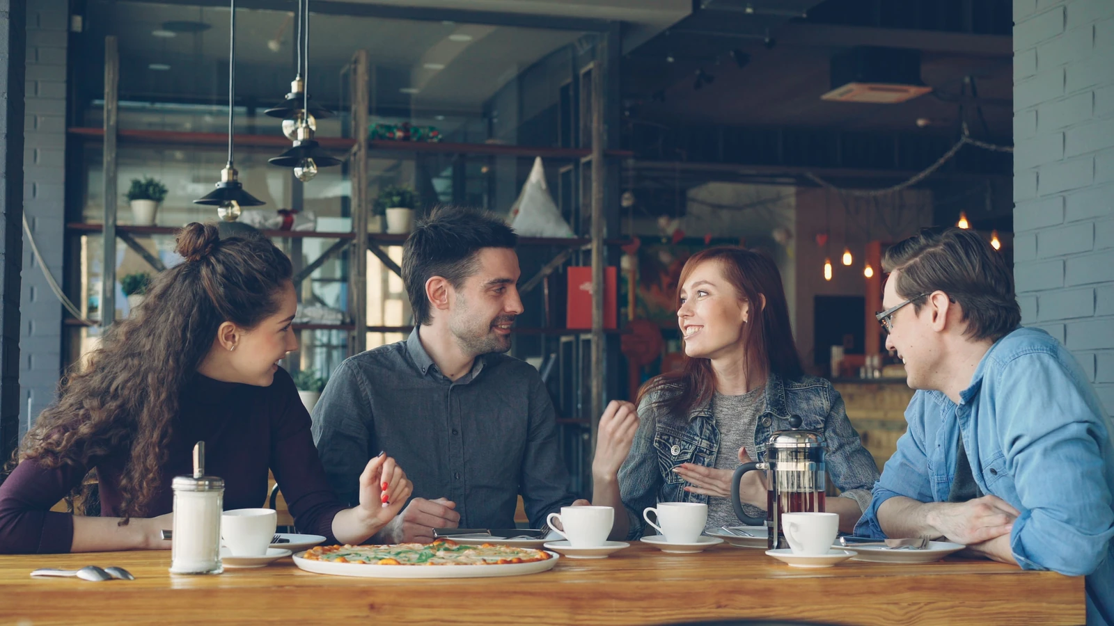 Gruppo di amici che ridono e chiacchierano davanti a un caffè in una elegante caffetteria