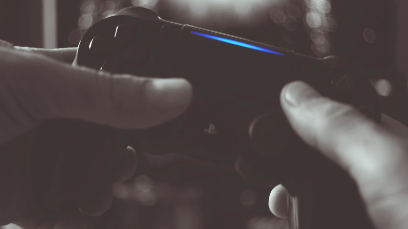 Foto in bianco e nero di un uomo che tiene il controller wireless Sony PS4 — George Becker – Pexels