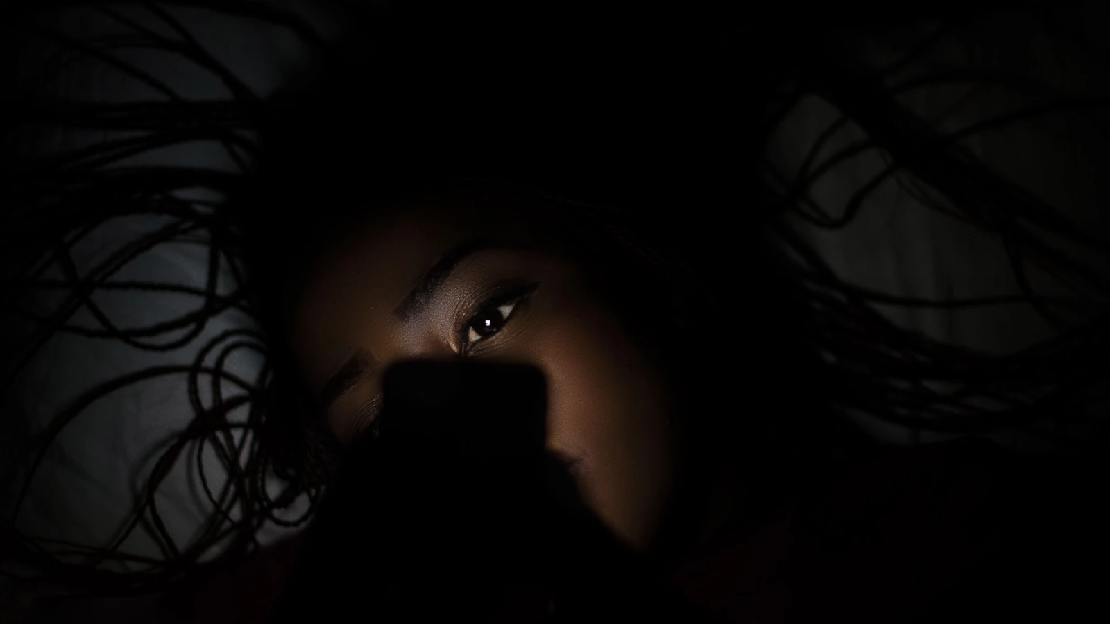 Donna sdraiata sul letto che tiene uno smartphone — Lombe K – Pexels