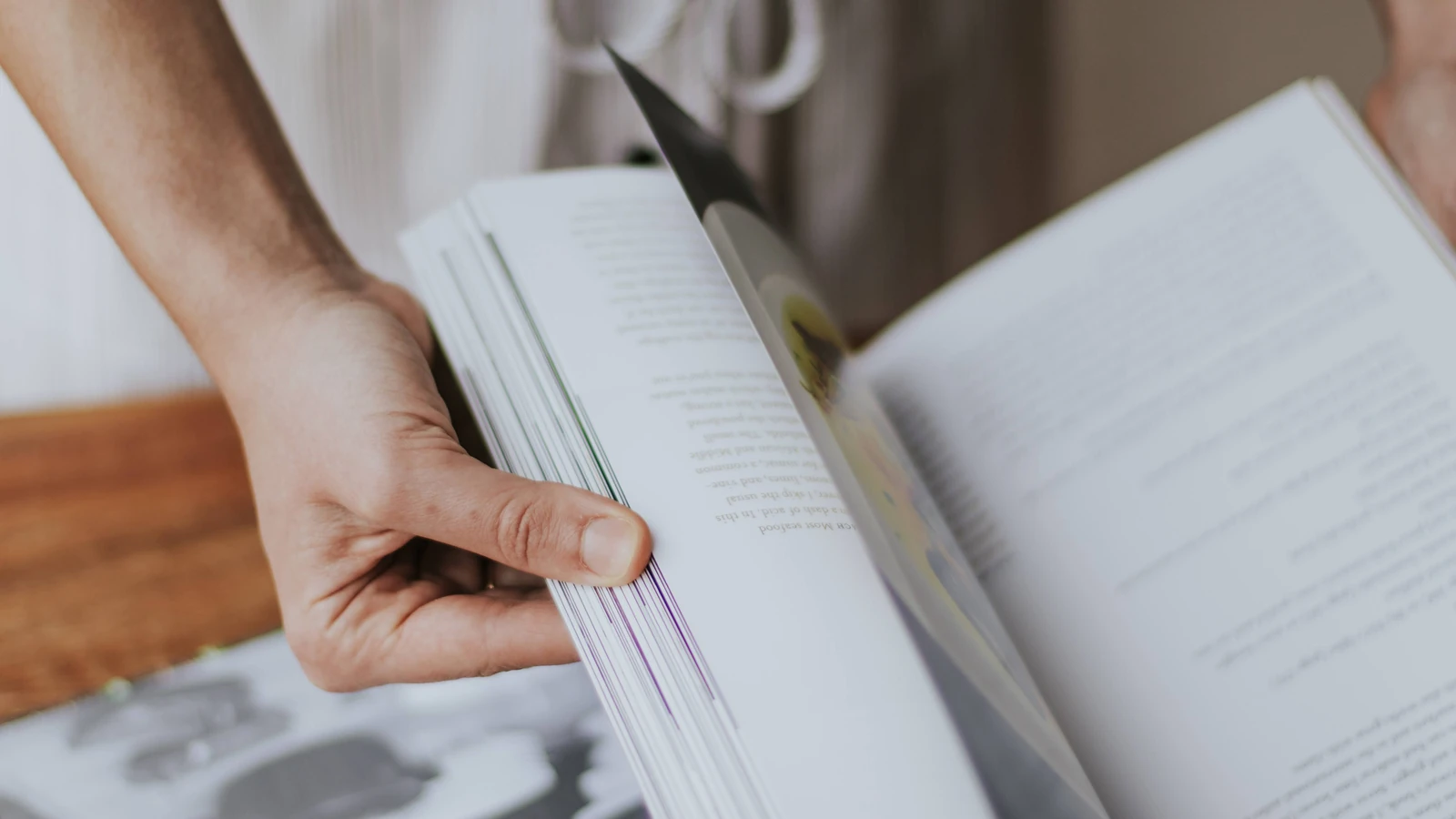 Una persona sfoglia un libro, dimostrando concentrazione e coinvolgimento nella lettura.