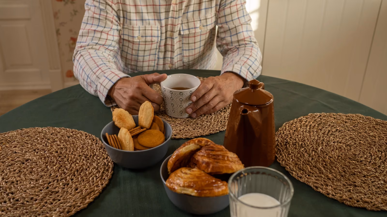 Un uomo anziano mentre beve caffè con biscotti e dolci a un tavolo per la colazione. — Ron Lach – Pexels