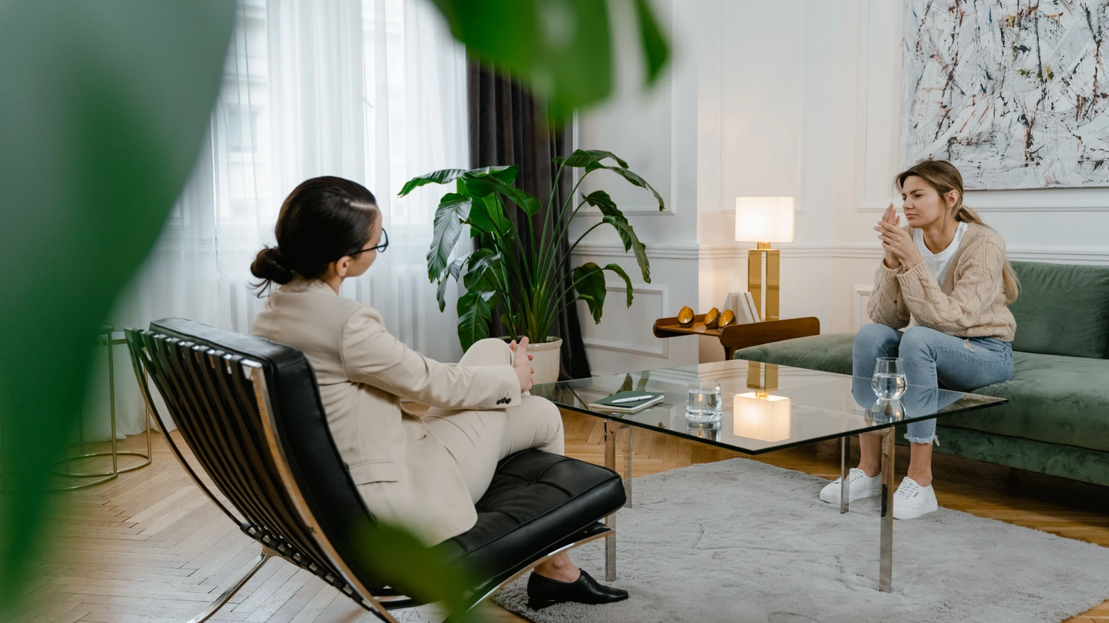 Una donna in terapia, seduta di fronte a un terapeuta in un ambiente da ufficio moderno, che esprime sentimenti.