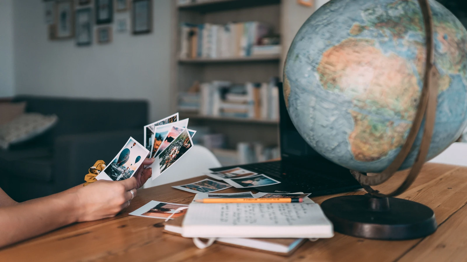 Una scena accogliente per esplorare i ricordi di viaggio con foto Polaroid, un mappamondo e appunti.