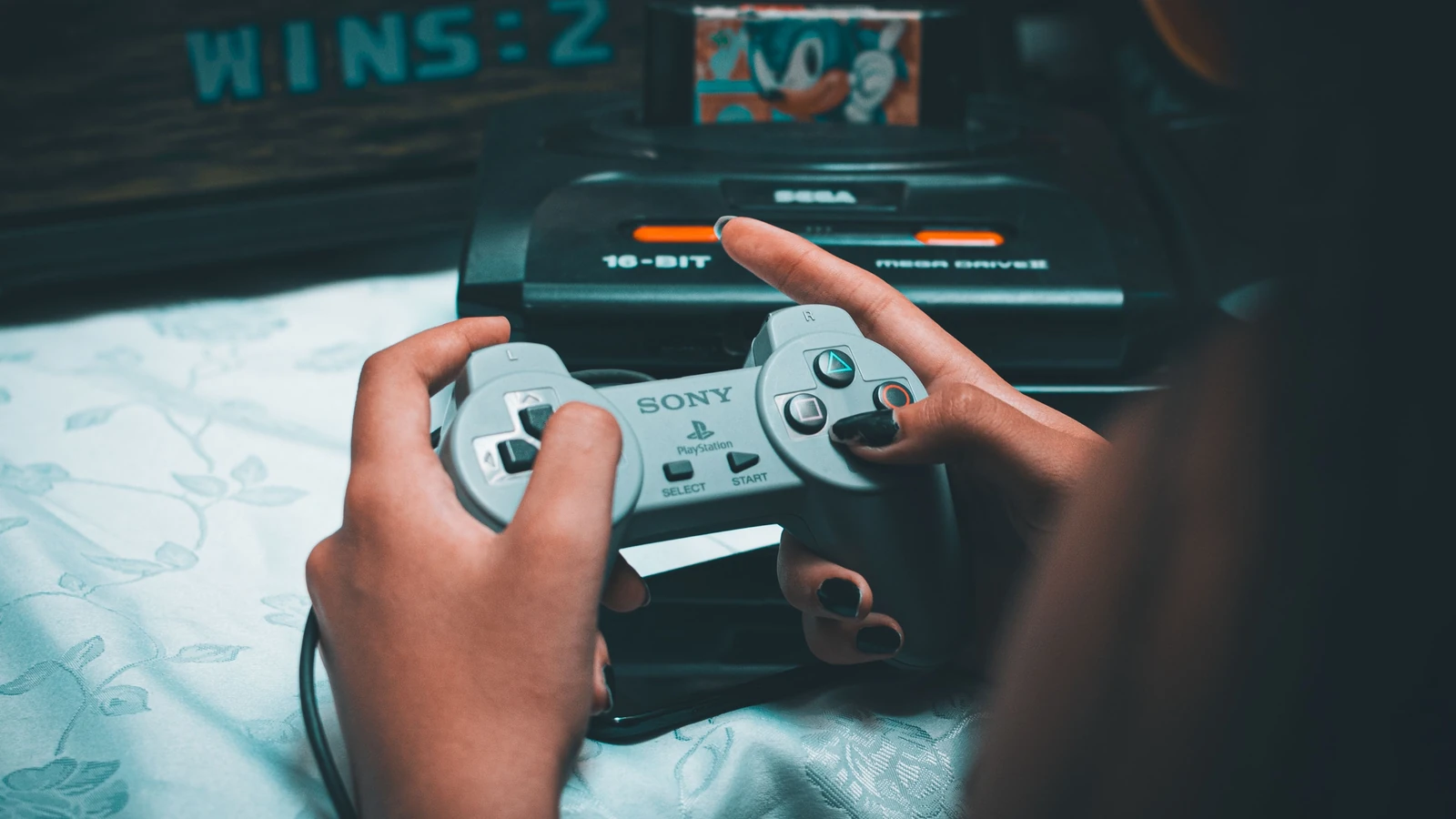 Mani che tengono un controller retrò Sony mentre giocano con la console