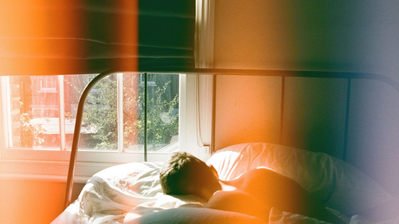 Un uomo che dorme pacificamente in una camera da letto a Londra, avvolto da una morbida luce mattutina. — Emma Filer – Pexels